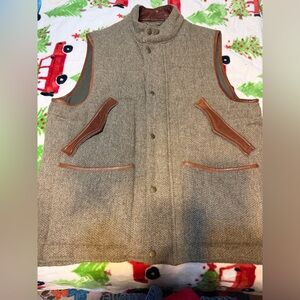 Orvis men's herringbone wool hunting vest with brown leather trim.